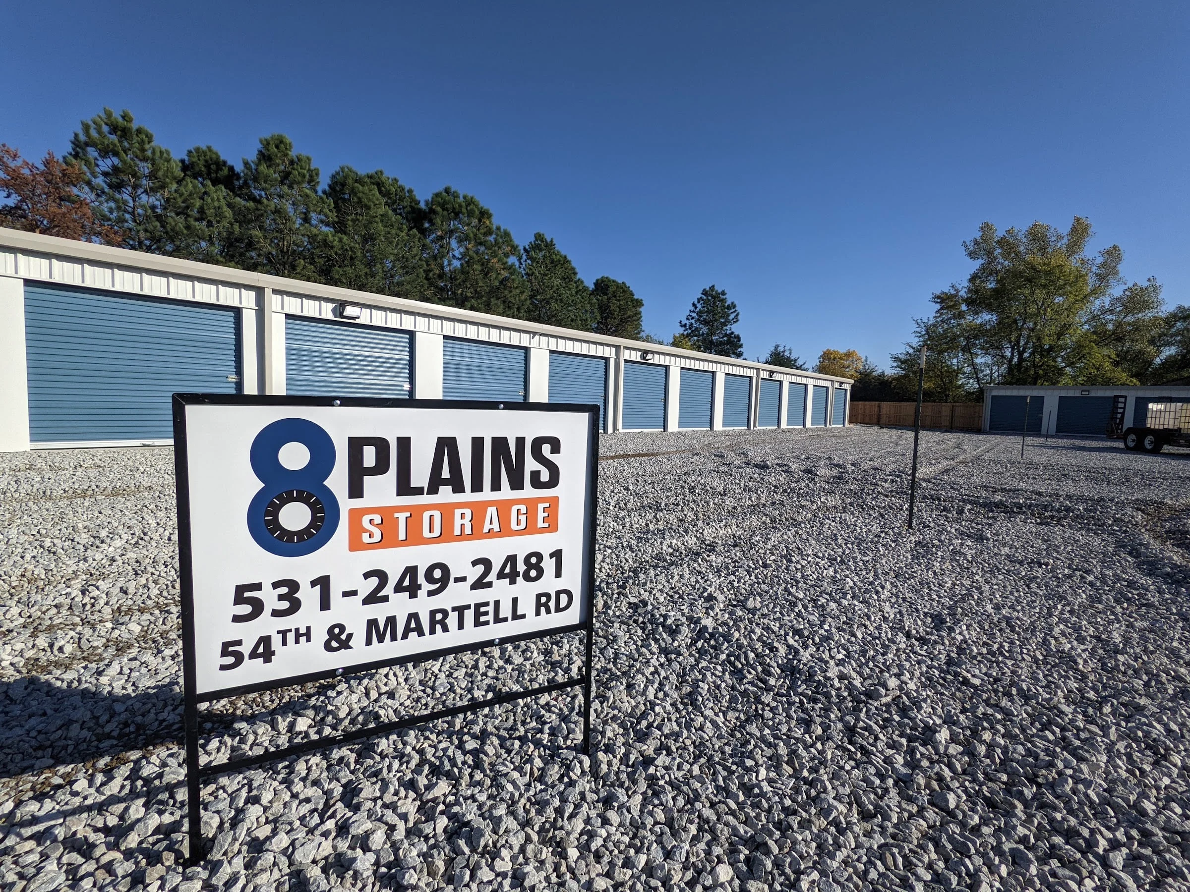 Entrance sign in front of rows of blue-door storage units