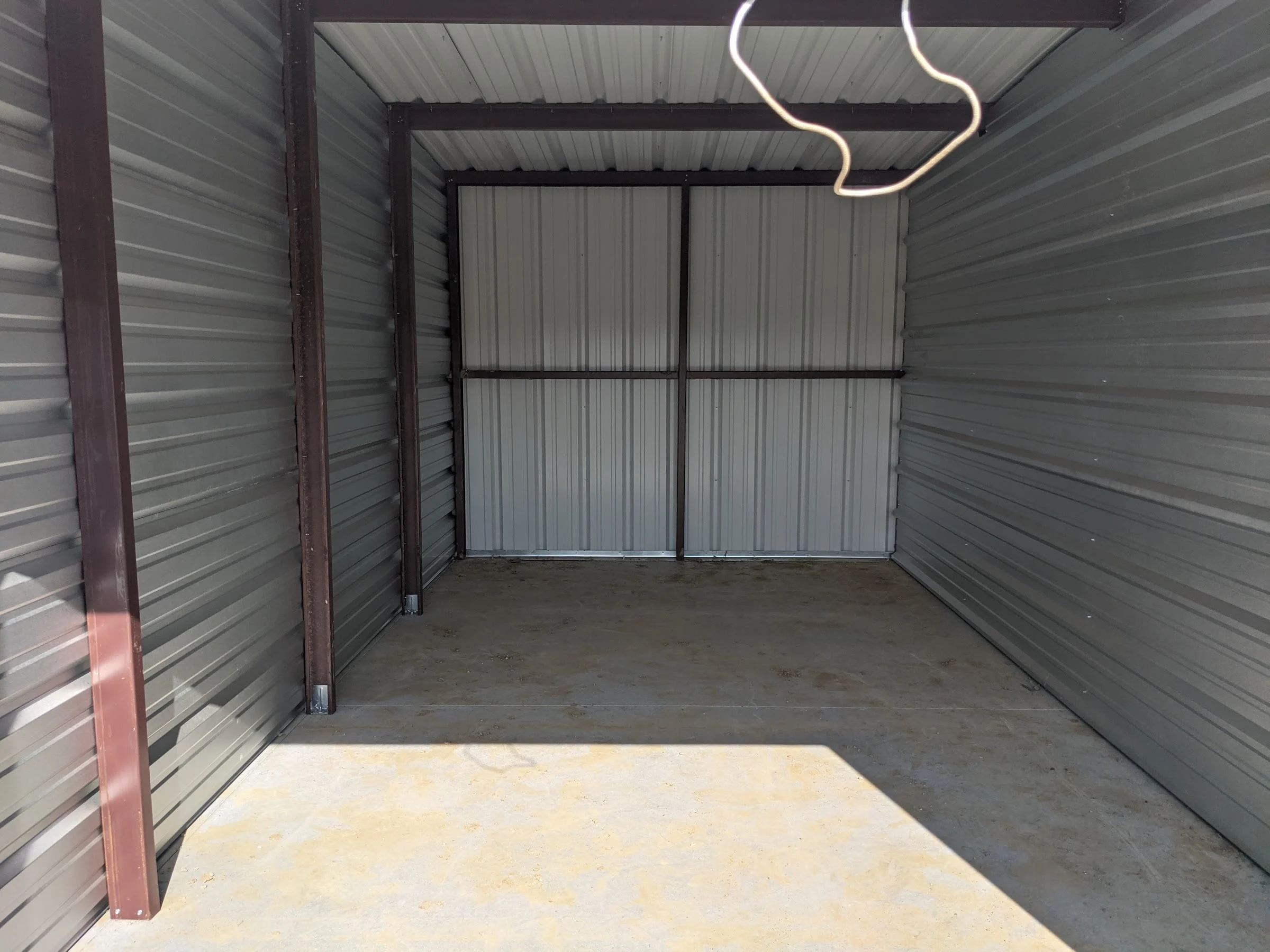 Inside an empty storage unit with steel walls and a concrete floor