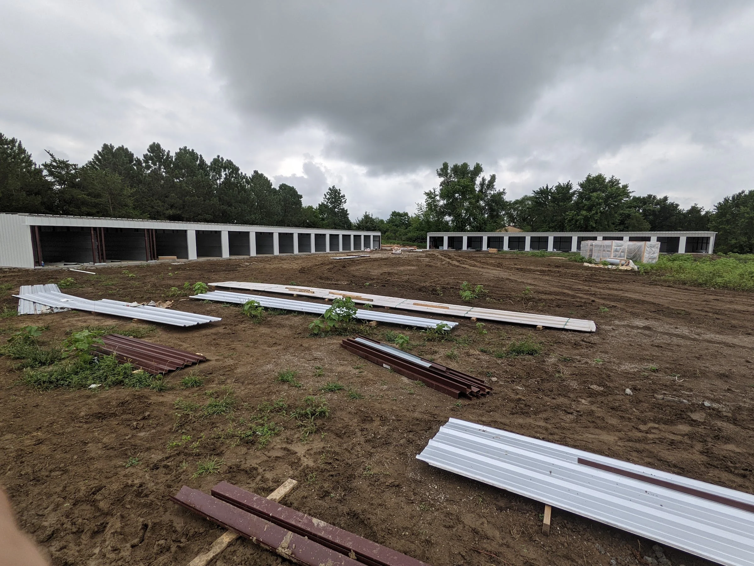 Steel panels and framing laid out beside storage buildings under construction
