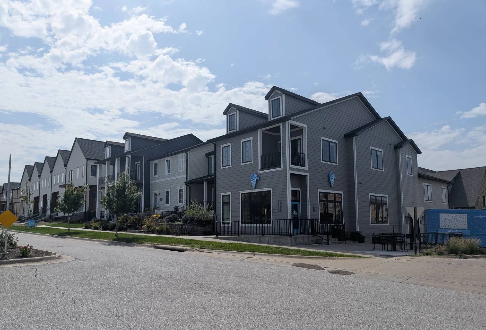 Row of three-story live/work buildings with dormers in Village Gardens; the corner unit has a ground-floor storefront