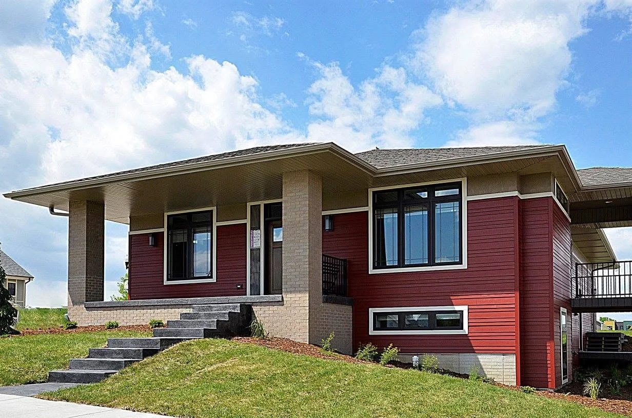 Ranch-style home with red siding, stone columns, and a covered front entry
