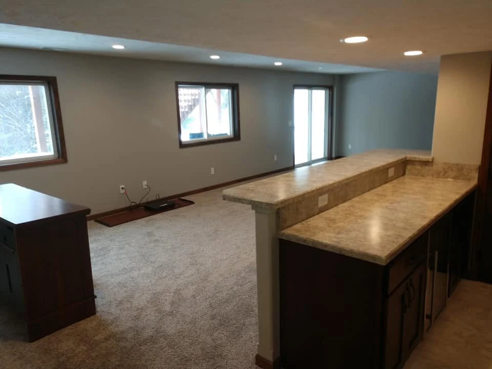Finished basement family room with carpet, egress windows, and a two-level bar counter