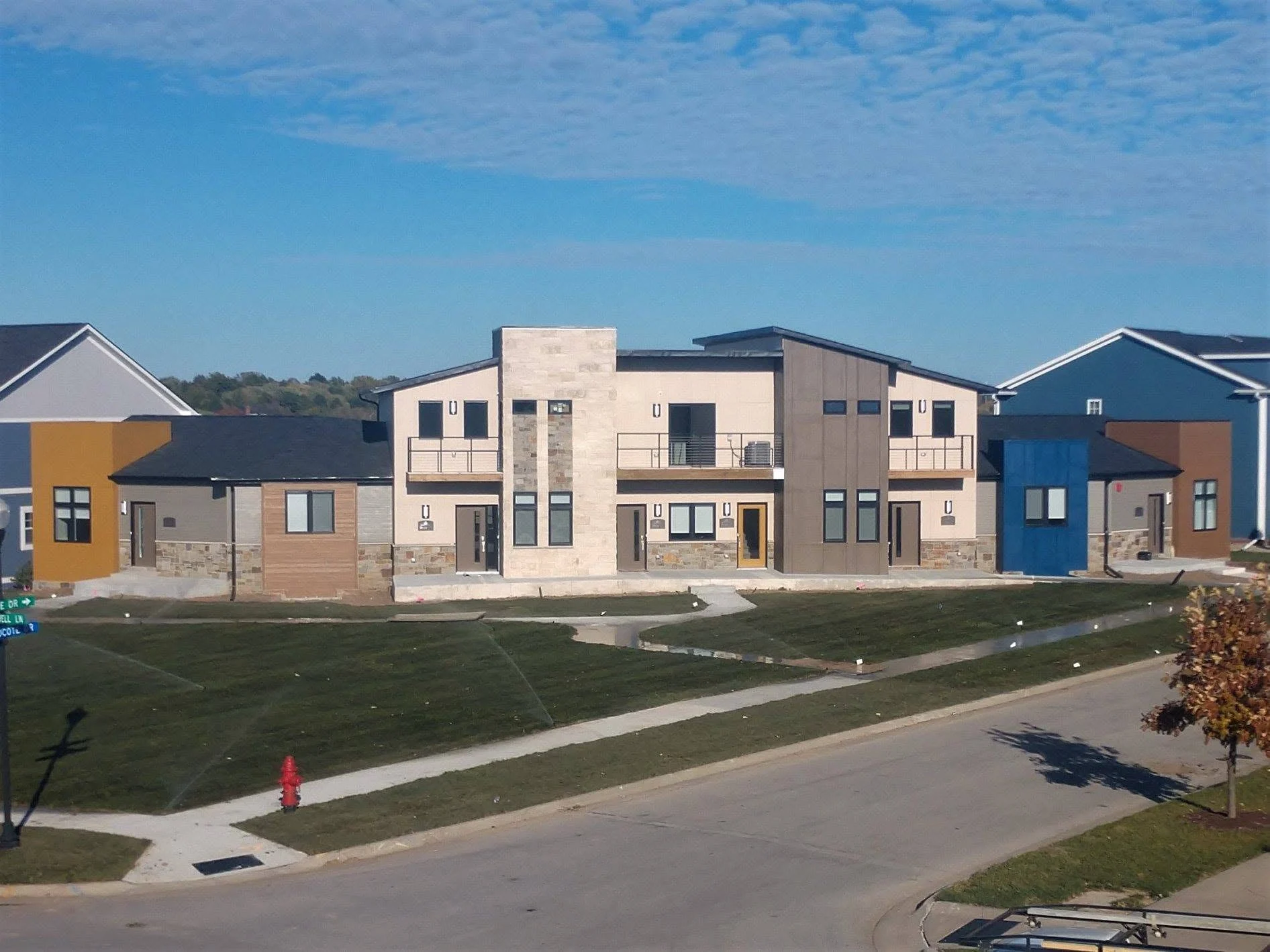 Row of new multi-family buildings with mixed siding and stone along a neighborhood street
