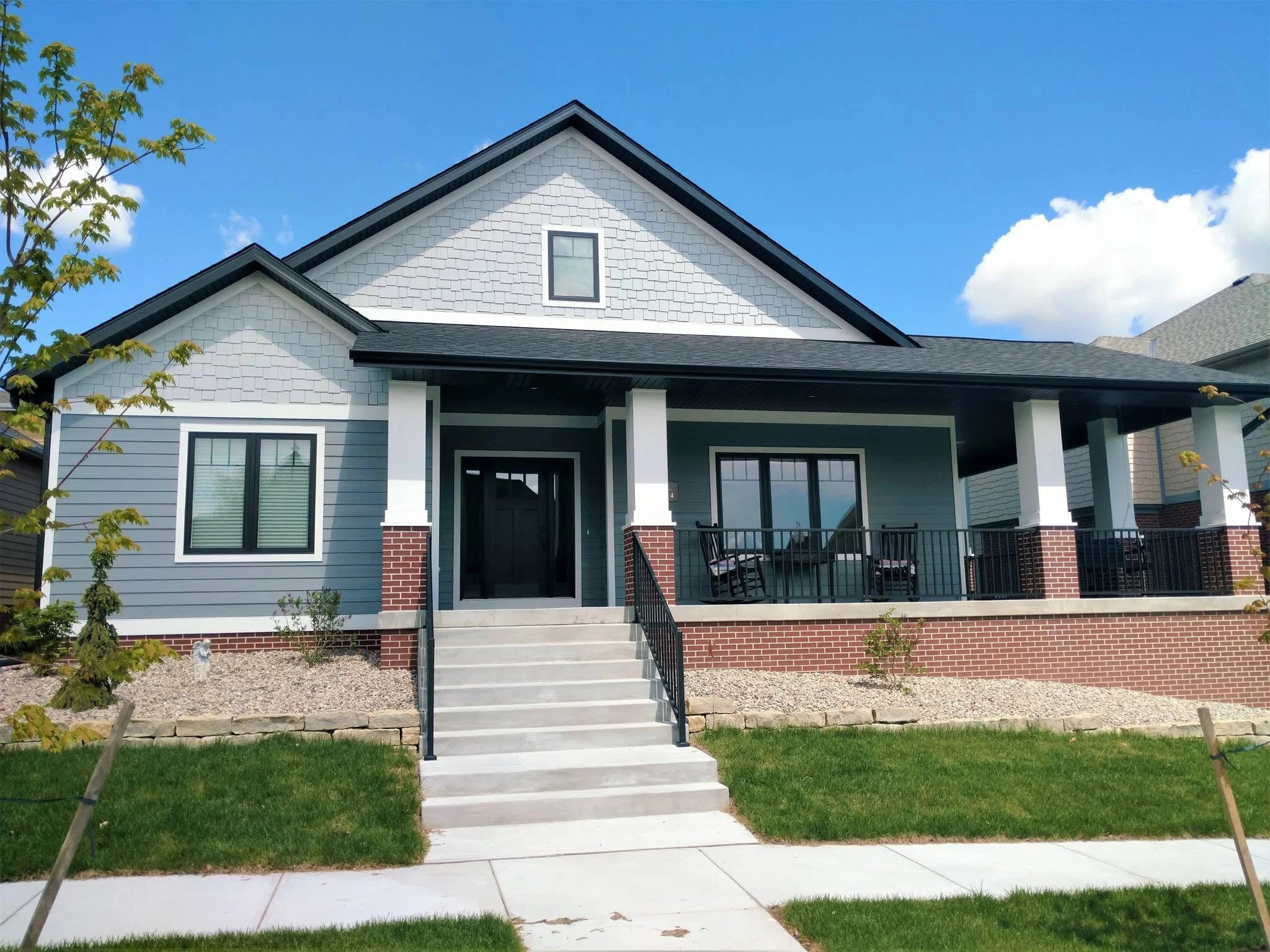 Craftsman-style home with a covered porch, white columns on brick piers, and a wide front stair