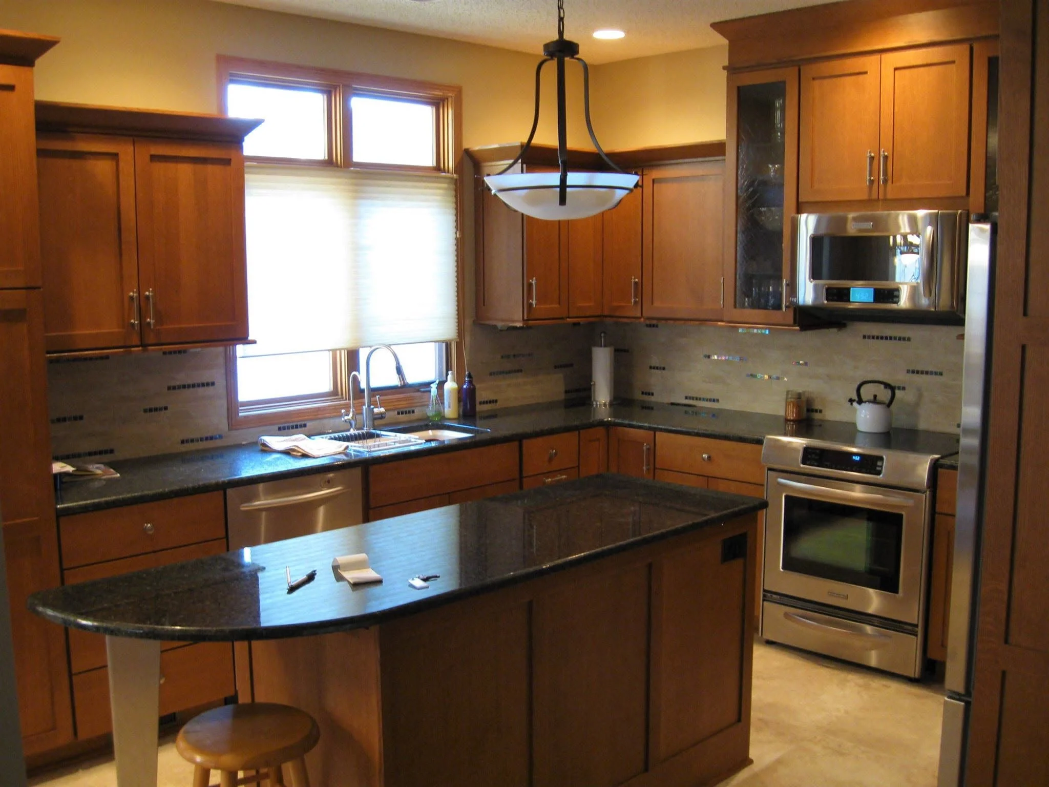 Kitchen with cherry cabinets, dark granite counters, and an island